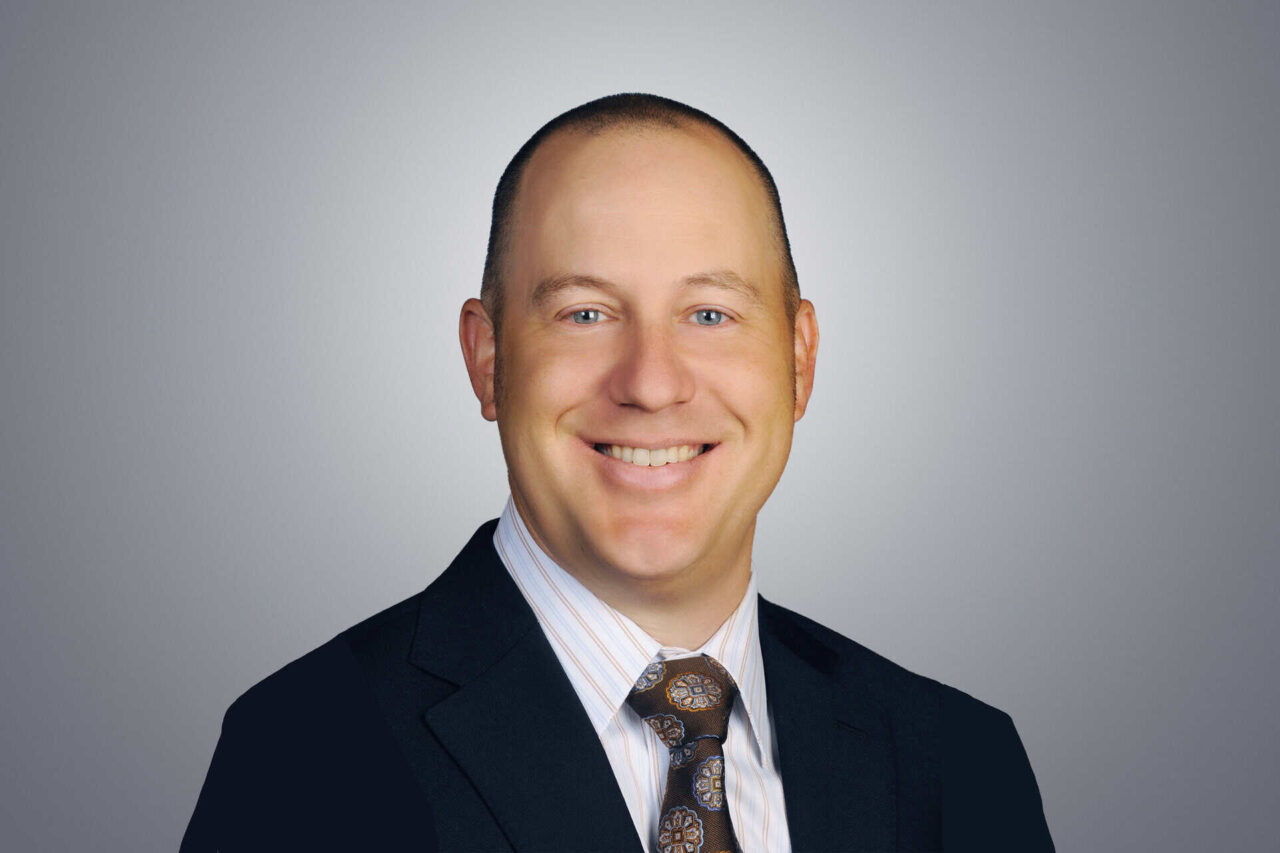 Smiling man in a suit, enhancing connections for manufacturers, distributors, and end users to grow.