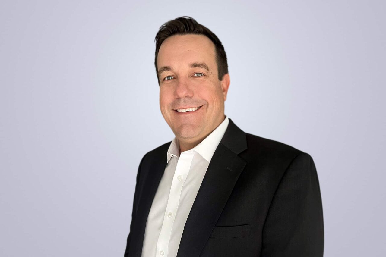 Smiling professional in a suit, exemplifying confidence in helping manufacturers and end users grow.