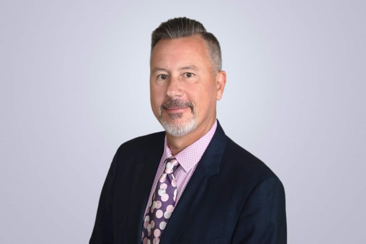 Business professional in suit and tie, representing helping manufacturers, distributors, and end users grow.