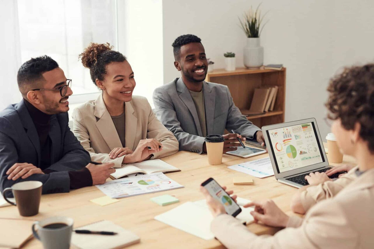 Colleagues in a meeting smiling, discussing charts on a laptop, illustrating careers that connect your skills.
