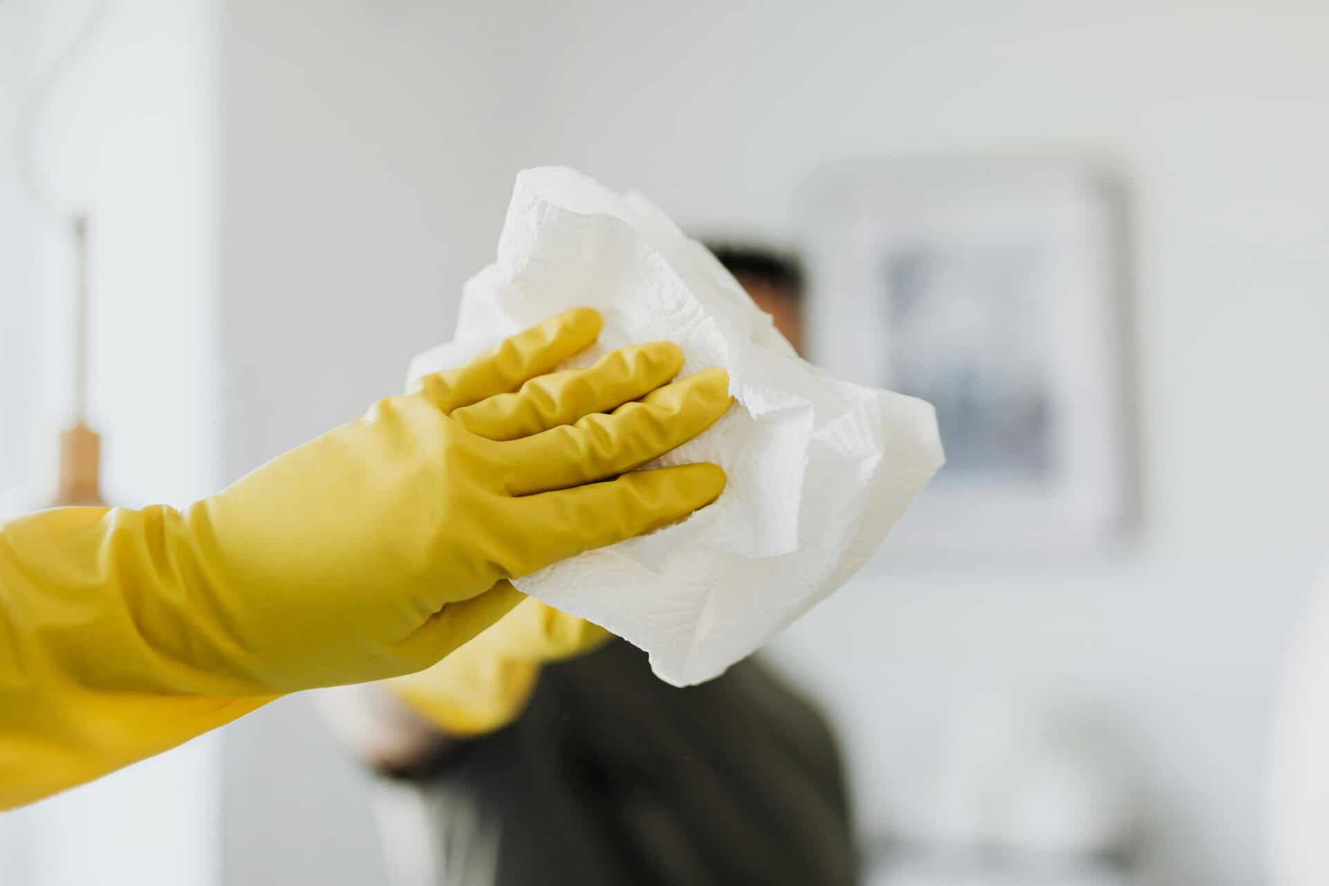 Yellow-gloved hand holding a white cloth, emphasizing a clean and organized work environment at Avision.