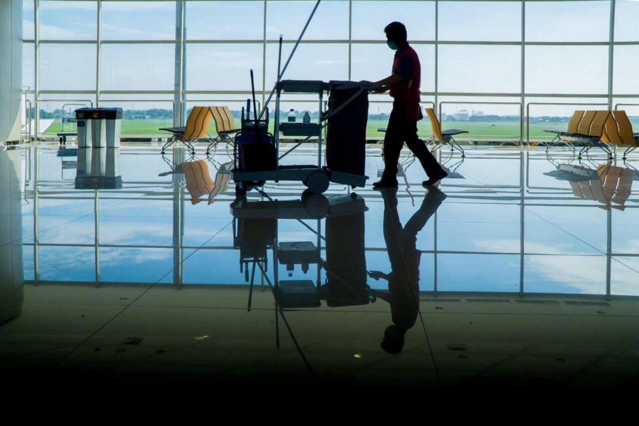 Janitorial staff pushing a cleaning cart in a bright, spacious facility, highlighting janitorial supplies solutions.