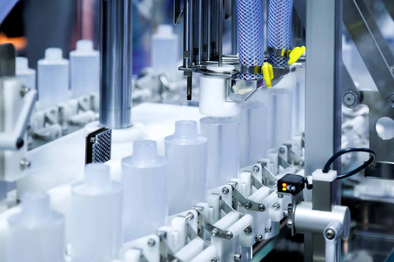 Automated machinery filling bottles on a production line, illustrating janitorial manufacturers' market expansion.