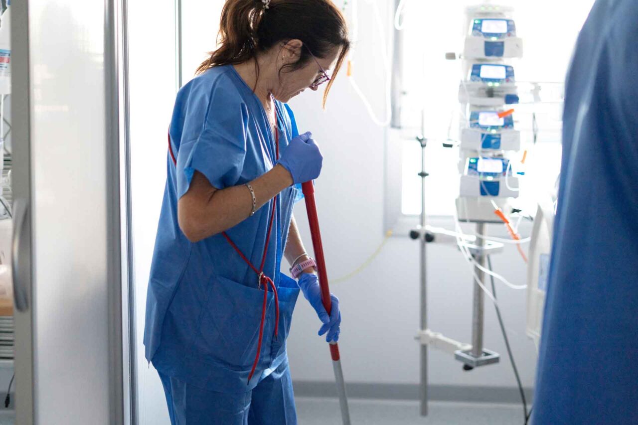 Healthcare worker in blue scrubs cleaning a medical room, showcasing trusted janitorial solutions through our network.