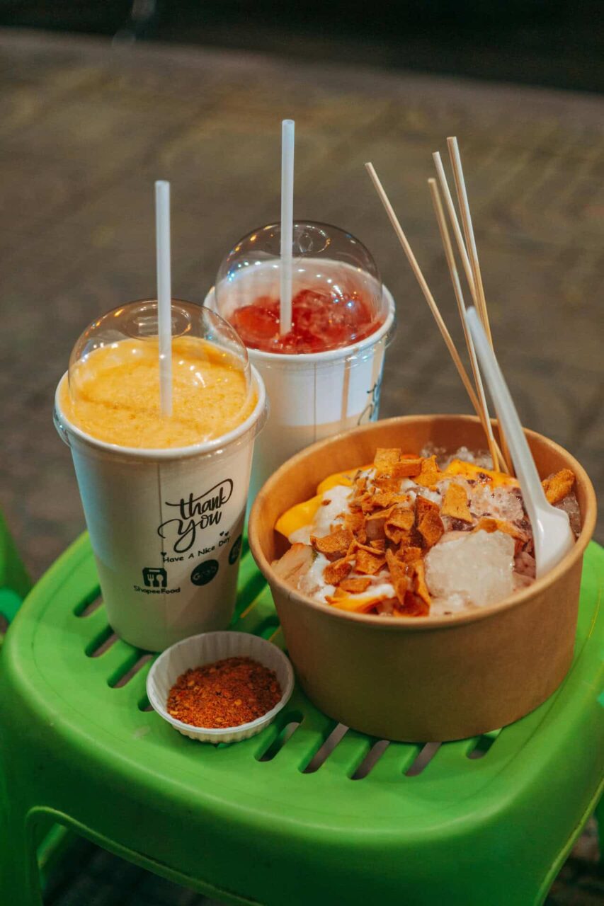 Two cups of iced drinks and a bowl of shaved ice dessert on a green table, showcasing food service supplies.