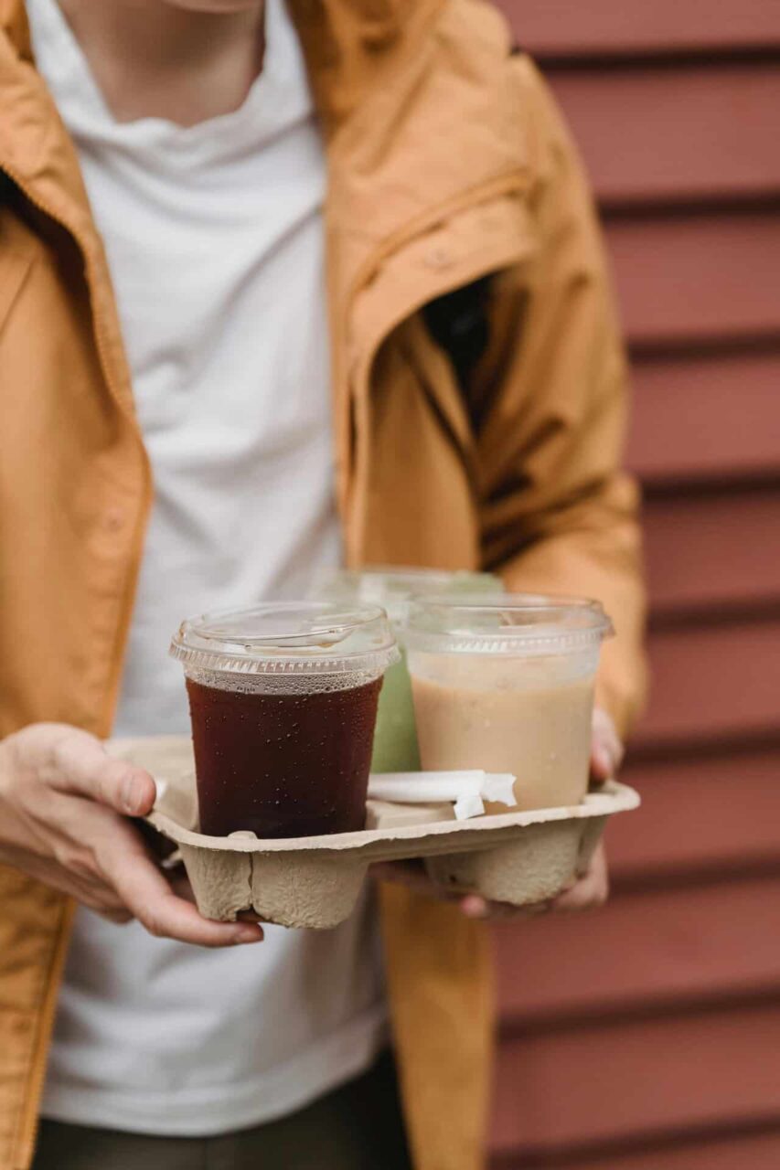 Carrying a tray with iced coffee drinks, highlighting food service supplies and packaging solutions.