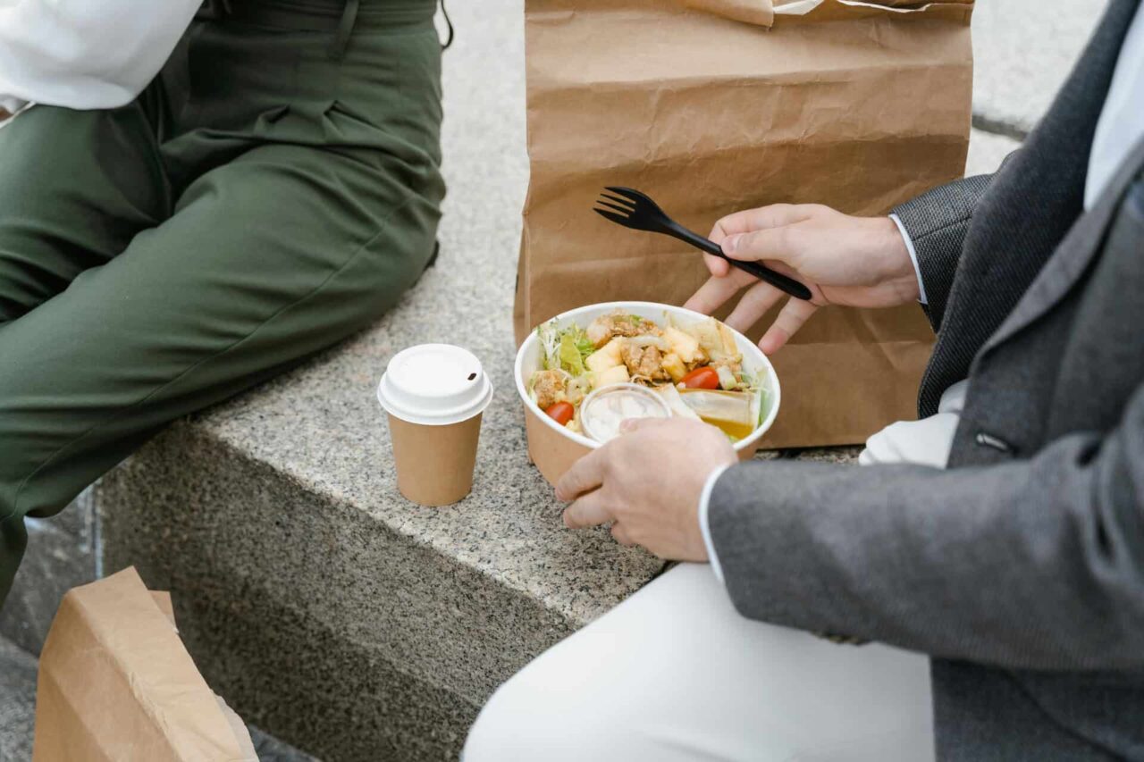 Two people enjoying a salad and coffee outdoors, showcasing packaging food service supplies through our local experts.